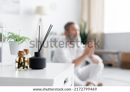 selective focus of aroma sticks and essential oils near master guru meditating on blurred background Royalty-Free Stock Photo #2172799469