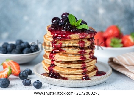 Delicious oatmeal pancakes with berry fruit blueberry strawberry jam dessert topping. Blue background Royalty-Free Stock Photo #2172800297