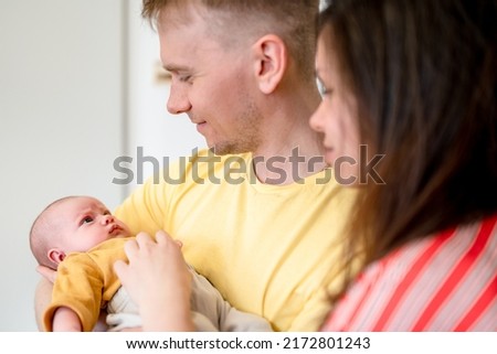 Happy young family with dad, mom and newborn baby in the baby's room