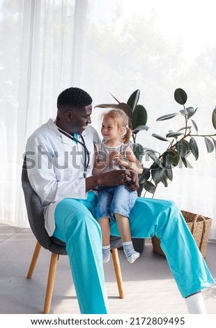 an African-American doctor communicates with a little girl patient. Royalty-Free Stock Photo #2172809495