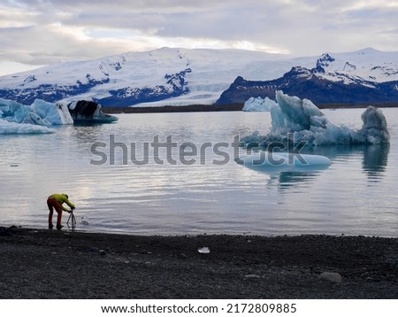 Man taking picture of ice block in Jökulsarlon  glacier lagoon at sunset, Iceland. High quality photo
