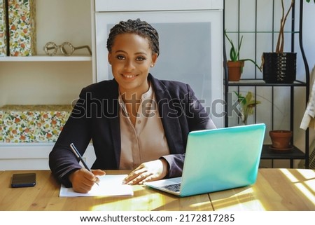 Young adult black executive businesswoman signing contract for client smiling looking at camera in office shot