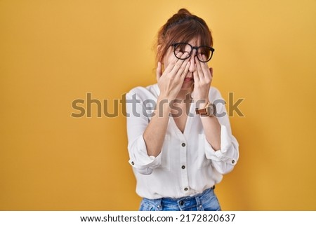 Young beautiful woman wearing casual shirt over yellow background rubbing eyes for fatigue and headache, sleepy and tired expression. vision problem 