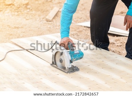 Worker use electric circular saw cutting plywood for concrete formwork at construction site.  Royalty-Free Stock Photo #2172842657