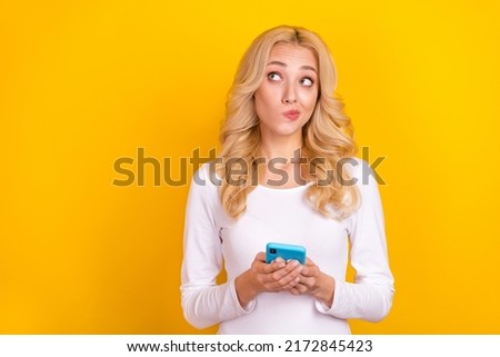Photo of unsure milennial blond lady hold telephone look promotion wear trend cloth isolated on yellow color background