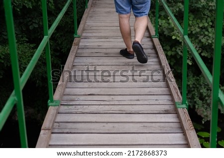 A male feet walking on a wooden bridge in the nature