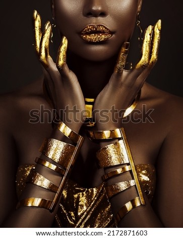 art fantasy portrait african american woman. female hands close-up, fingers in golden paint. Girl queen Cleopatra style. greek gold bracelets. Creative metallic professional makeup lips diamonds gloss Royalty-Free Stock Photo #2172871603