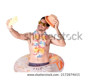 Portrait of a young smiling tourist with a flower necklace and sunglasses wearing an inflatable float takes off his hat and poses for a selfie photo