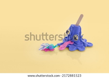 Creative concept with ice cream on a stick and a fly. Ice cream from a plate and a fly on a bright yellow background. Purple ice cream with eyes
