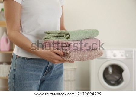 Woman with folded clean terry towels in laundry room, closeup Royalty-Free Stock Photo #2172894229