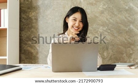 Looking to camera, Happy young asian freelance people business female working with laptop computer in the office.