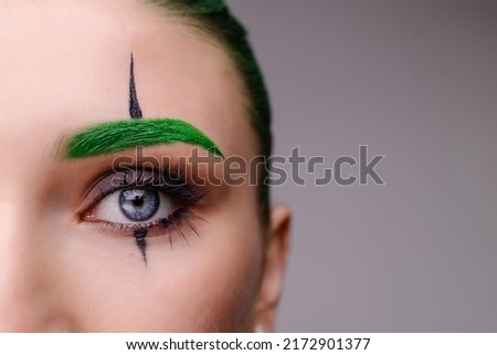 stylish trendy trendy halloween makeup. Eye close-up macro. Clown costume for a masquerade. The concept of emotions of anger, envy, madness. Green background place for banner text. Creepy scary