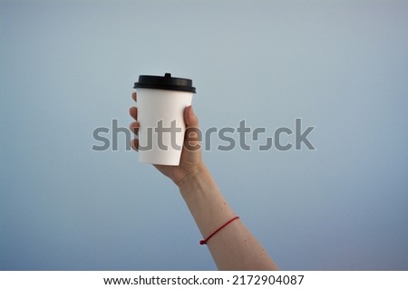 A paper cup of coffee in the hand. White paper cup of coffee in hand. For mock up. Isolated. On colored background