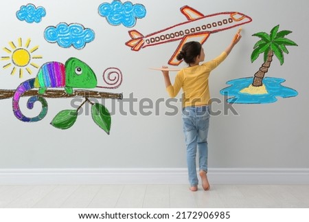 Cute child girl painting plane on light grey wall indoors