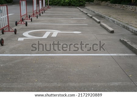 Handicap parking sign painted white on the street with traffic barrier made of white-red steel and Black wheels crossed. Special parking space reserved for wheelchairs.