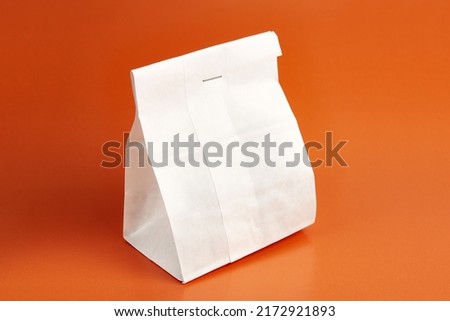 Paper bag with tea. Packaging for dry products on an orange background.
