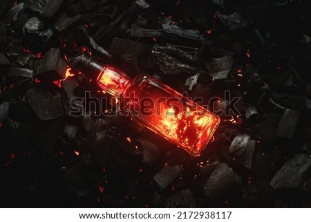 Bottle of whiskey on the blazing charcoals background. Top view.  Royalty-Free Stock Photo #2172938117
