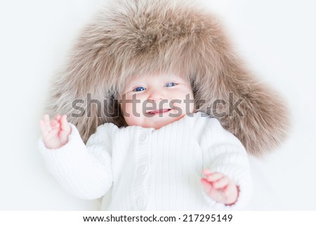 Sweet laughing baby in a big fur hat