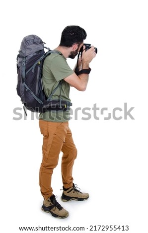 Back view of a male tourist with backpack taking a picture with the camera isolated on white background. Rear view of mountaineer photographer taking picture. 
