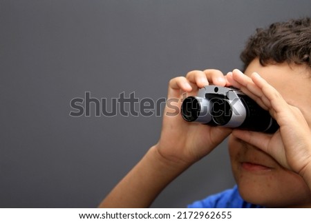 boy looking  through binoculars on grey background with people stock photo 