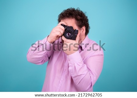 Funny fat man and camera. A young attractive guy is taking pictures. 