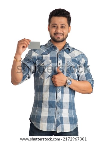 Young smiling handsome man posing with a credit or debit card on white background.