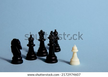 One chess piece against black chess pieces on a blue background with contrasting shadows. Abstract background. Concept of leadership