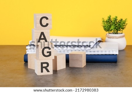 cagr word written on wooden cubes with copy space, yellow background. cagr - compound annual growth rate