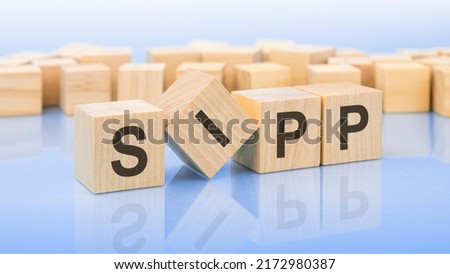 four wooden blocks with the letters SIPP - on the bright surface of a blue table. the inscription on the cubes is reflected from the surface. sipp - short for self-invested pension plan