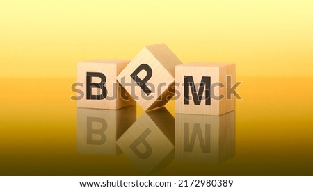 wooden blocks with text BPM on yellow background. bpm - short for business process management Royalty-Free Stock Photo #2172980389