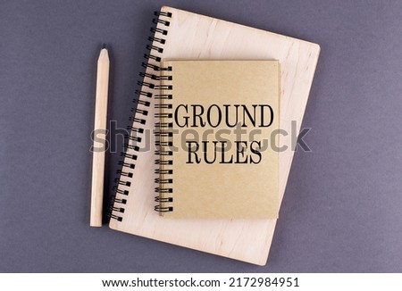 Word GROUND RULES on a notebook with pencil on the grey background