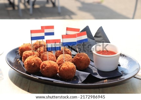 Dutch Bitterballen with mustard, warm stuffed fried meatballs, served in the Netherlands and decorated with the dutch flag Royalty-Free Stock Photo #2172986945