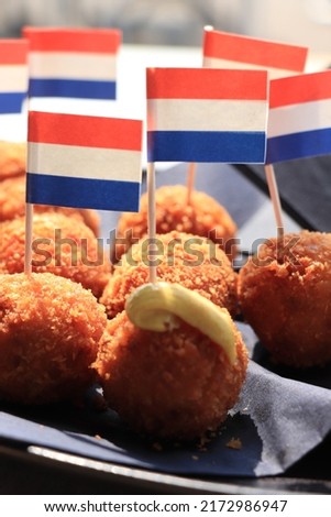 Dutch Bitterballen with mustard, warm stuffed fried meatballs, served in the Netherlands and decorated with the dutch flag Royalty-Free Stock Photo #2172986947