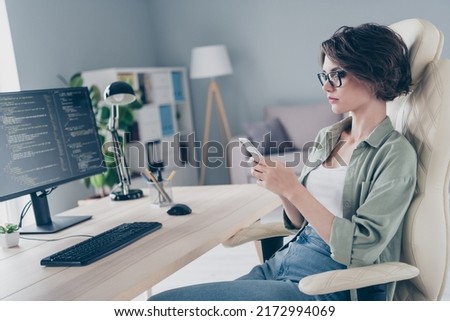 Profile side photo of beautiful female it worker have break surfing online in phone sitting leather armchair in office