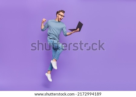 Photo of busy lucky guy wear grey shirt spectacles jumping high writing modern device isolated violet color background