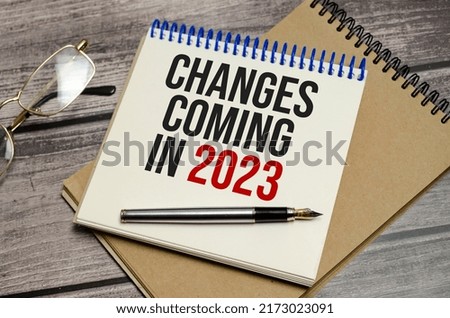 notebook with the word change is coming in 2023 on wooden background