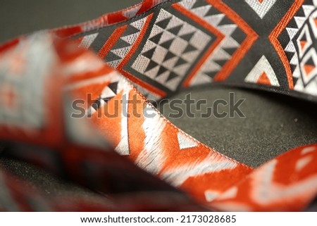 Both sides of a ribbon with a maori pattern on it. Royalty-Free Stock Photo #2173028685