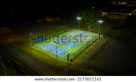 Evening aerial photo of outdoor blue tennis courts with pickleball lines with lights turned on.	 Royalty-Free Stock Photo #2173051161