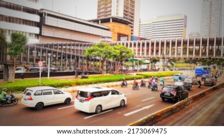 Defocused abstract background of busy vehicular traffic around the pedestrian bridge at the Senayan roundabout in Jakarta, Indonesia.