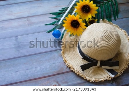 Straw hat, plastic bottle, plant, and sunflower on the right side of the picture