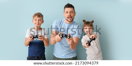 Father and his little children playing video games on light blue background