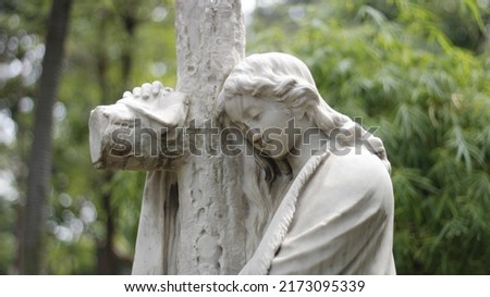 sad woman statue leaning on cross