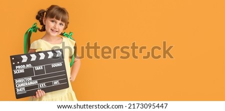 Little girl with movie clapper on orange background with space for text