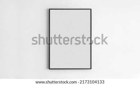 Black rectangular picture frame on white wall with blank paper in it. You can place your image in this frame. Interior photo. Painting, poster, photograph. Decorate your apartment in a modern style Royalty-Free Stock Photo #2173104133