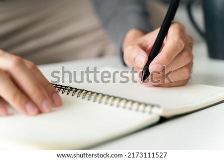 left handed man writes in a notebook on the table Royalty-Free Stock Photo #2173111527