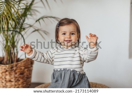 Pretty one year toddler girl in grey and white stripped dress posing in eco studio. Copy space. Royalty-Free Stock Photo #2173114089