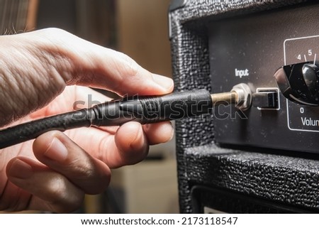 Plugging an instrument cable into a guitar amplifier Royalty-Free Stock Photo #2173118547