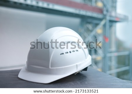 white hardhat, builder, architect helmet, work gloves on scaffolding, background of high buildings, protection inspecting at construction site for building renovation, civil engineering concept Royalty-Free Stock Photo #2173133521