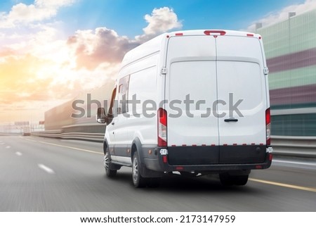 White mini bus is moving motion blur along city highway bypass road with beautiful sky before sunset. Fast express delivery service of goods and parcels Royalty-Free Stock Photo #2173147959