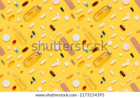 Seamless pattern of medical drugs tablets and pills assortment with ampoule glass bottle and band aid on yellow background top view flat lay Royalty-Free Stock Photo #2173154395